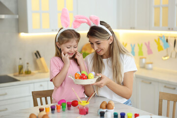 Obraz na płótnie Canvas Easter celebration. Happy mother and her cute daughter with painted eggs at white marble table in kitchen