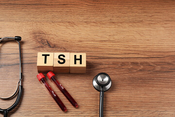 Endocrinology. Stethoscope, cubes with thyroid hormones and blood samples in test tubes on wooden...