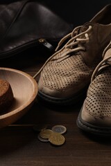 Poverty. Old shoes, bag, piece of bread and coins on wooden table - obrazy, fototapety, plakaty