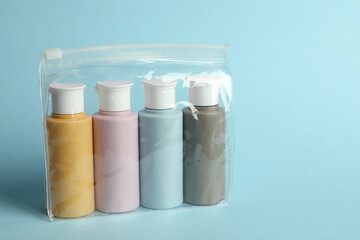 Cosmetic travel kit in plastic bag on light blue background. Space for text