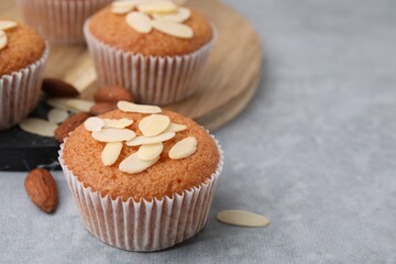 Muffins with fresh almond flakes and nuts on grey table, closeup. Space for text