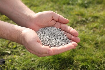 Man with fertilizer in hands outdoors, closeup