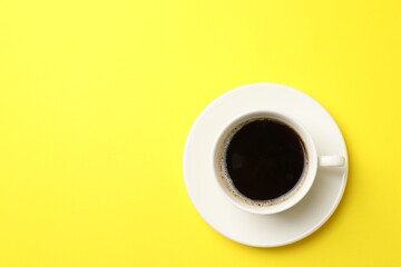 Cup of aromatic coffee on yellow background, top view. Space for text