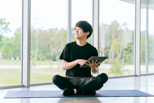 タブレット端末を使うスポーツウェア姿の若いアジア人男性
