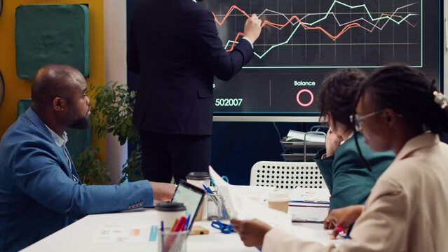 Project managers making a presentation with annual reports to evaluate statistics and understand what can be improved, problem solving meeting. Team identifying issues to ease workflow. Camera A.