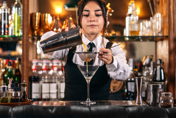 Female bartender preparing a cocktail in a traditional cocktail bar