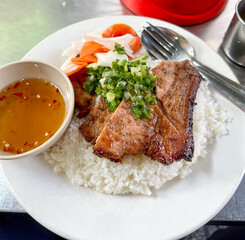 Com tam. Grilled pork over broken rice. A typical Vietnamese breakfast dish. Rice is cooked after being literally broken into small pieces. grilled pork ribs are placed on top. Serve with pickles,