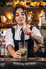 Female bartender preparing a cocktail in a traditional cocktail bar