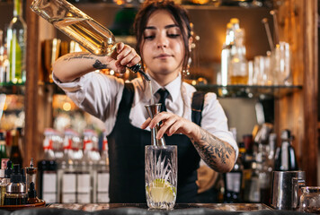Female bartender preparing a cocktail in a traditional cocktail bar