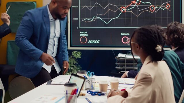 Skilled project team reviewing annual reports market trends in briefing meeting, knowing what to improve in order to guarantee customer experience and satisfaction. Enterprise development. Camera A.