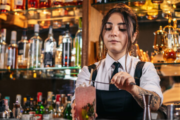 Female bartender preparing a cocktail in a traditional cocktail bar