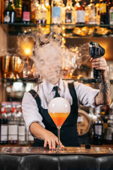 Stylish female bartender preparing a cocktail with a smoke bubble