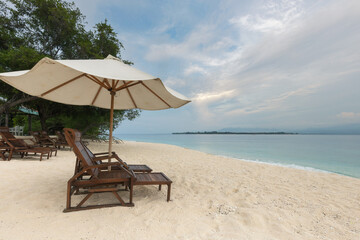 Sunbed and umbrella at the white sand beach of tropical paradise Gili Meno island in Lombok island,...