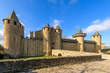 Front view of the bridge and facade of Château Comtal, the large, restored 12th-century hilltop castle, with a museum in medieval walled Carcassonne, France. - obrazy, fototapety, plakaty