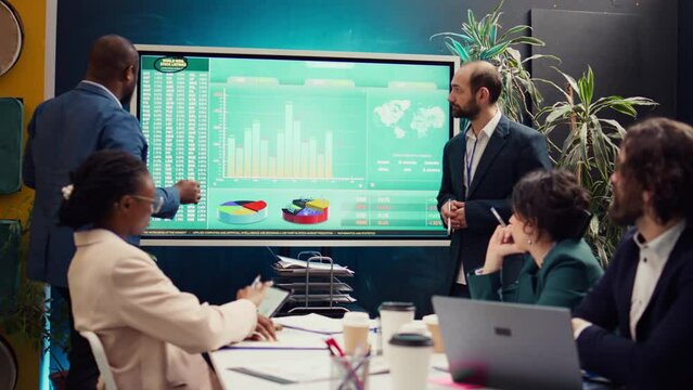 Marketing team gathering in a information sharing meeting to study updates on regulatory changes or industry standards. Business employees reviewing all data analysis reports. Camera B.