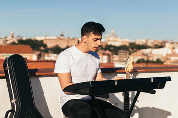 Side view of a man playing music keyboard on a rooftop
