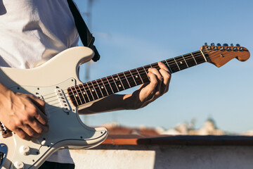 man playing electric guitar on a rooftop