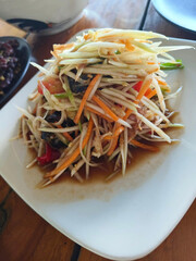 close up view of delicious asian food, papaya salad on table.