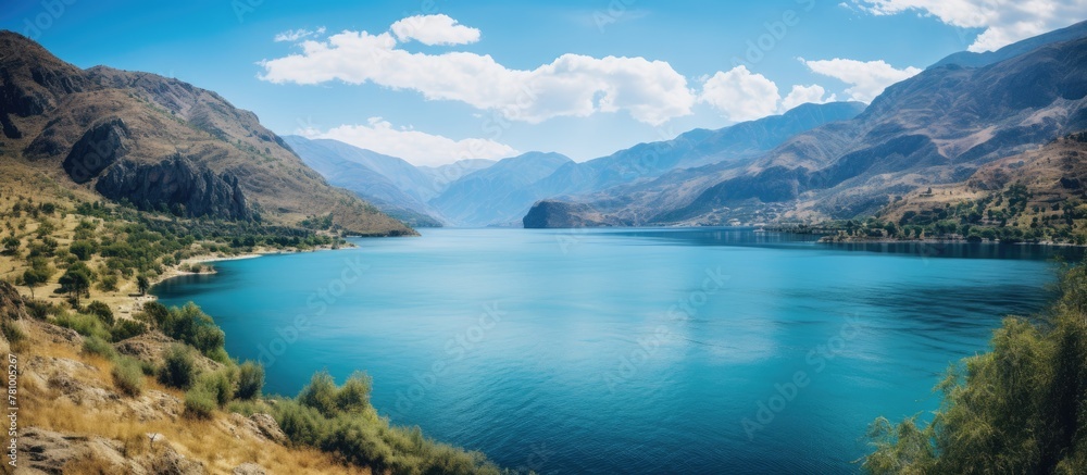 Sticker Scenic view of a tranquil lake nestled amidst majestic mountains and lush foliage