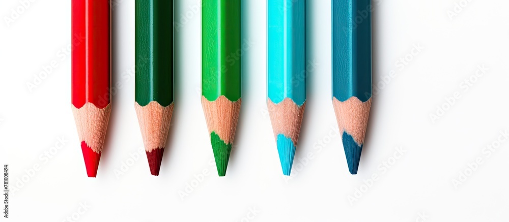 Poster four different colored pencils are neatly arranged in a row on a simple white surface