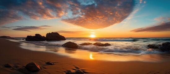 Golden sunset casting warm hues on ocean waves crashing against rocks on the beach