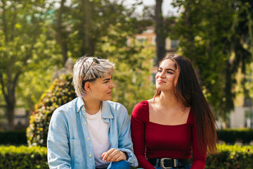 two teenager girls sitting in a park talking