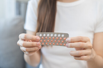 Contraception and pregnancy, menstruation concept, birth control pills asian young woman hand holding hormonal oral contraceptives medicine, take pharmaceutical to prevention, safe virus sex disease.