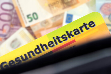 Versichertenkarte einer Krankenkasse und Euro Geldscheine im Hintergrund