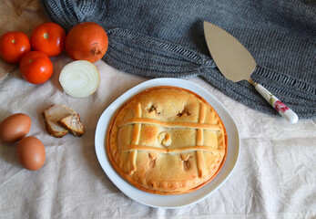 Freshly made round empanada accompanied by tomatoes, tuna, egg and onions.