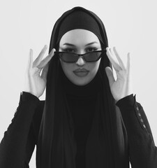 Portrait of beautiful stylish young muslim woman wearing black hijab and sunglasses as modern eastern fashion concept posing on white background. - 781032498