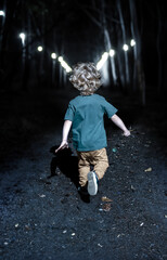 A little boy runs down a dark alley lit by lamps