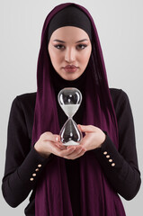 Beautiful arab businesswoman wearing hijab and holding sand clock. Time is passing and it's a pressure concept. - 781037095