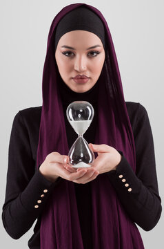Beautiful arab businesswoman wearing hijab and holding sand clock. Time is passing and it's a pressure concept.