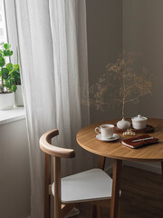 Cozy morning, coffee break - a cup of coffee, a notebook, a hair clip, decor on a round wooden table in the living room