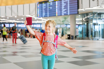 Little preschool girl at airport terminal. Happy child going on vacations by airplane. Smiling kid...