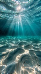 Underwater view of sunbeams filtering through crystal-clear water, illuminating a sandy ocean floor