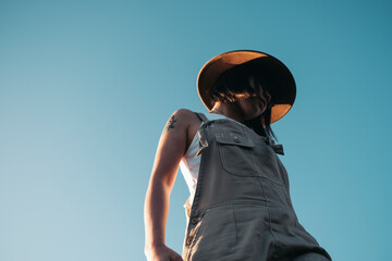 Low-angle closeup portrait of a Blue glowing sky with a young woman in summer casual cloth
