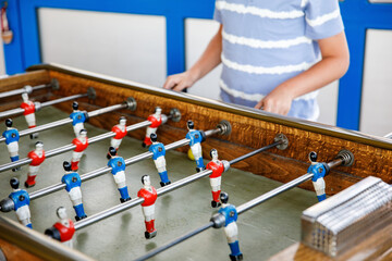 Close-up of kid boy playing table soccer. Happy excited child having fun with family game with...