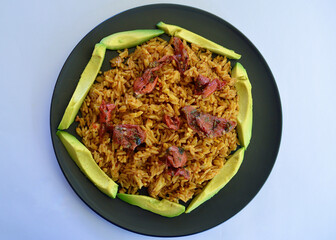 Spicy Mexican style rice with sliced avocado and sun dried tomatoes in a plate.