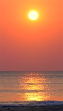 Sunset over ocean horizon with vibrant orange sky reflecting on tranquil water surface. Peaceful evening seascape for relaxation and nature backgrounds. Timelapse