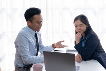 Asian businesswoman and businessman talking, explaining, discussing in the office.