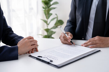 Lawyer in suit reviewing important legal documents with a client in a professional office.