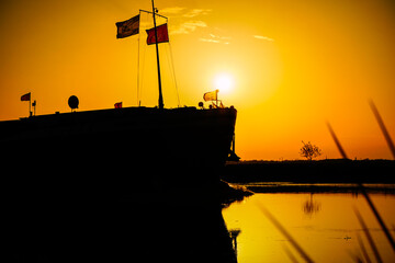 Binnenschiff im Sonnenuntergang auf der Hunte in Hude, in der Nähe von Oldenburg.