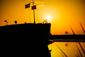 Fotobehang Binnenschiff im Sonnenuntergang auf der Hunte in Hude, in der Nähe von Oldenburg. © Frank