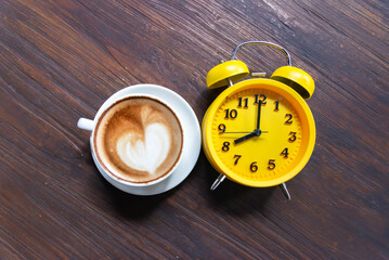 Coffee in a cup with an alarm clock. Awakening concept a boost of energy for the whole day.