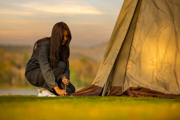 Woman sets up tent during in nature with sunset background. A method of attaching a sling when...