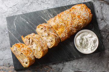 Austrian appetizer strudel with chicken, mushrooms and cheese served with sauce close-up on a board...