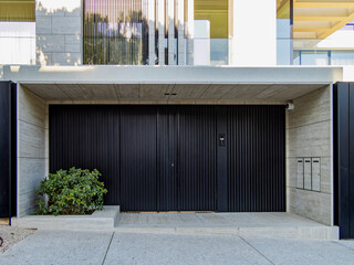 A modern design residential building front and entrance with a black painted iron door at the posh...