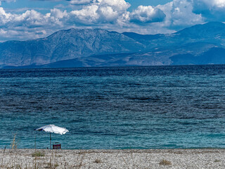 A lonely umbrella on a tranquil beach with blue sea and under a spectacular sky. Summer is coming. - 781087872