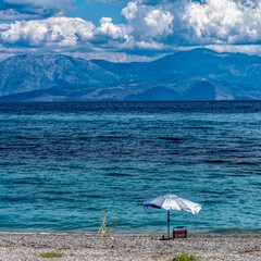 A lonely umbrella on a tranquil beach with blue sea and under a spectacular sky. Summer is coming. - 781087888